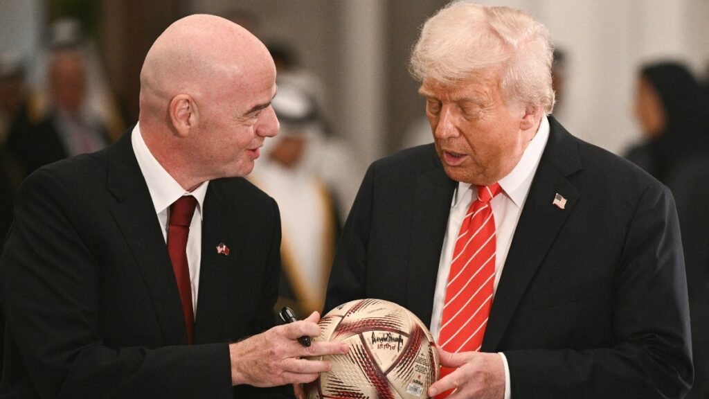 El presidente de la FIFA, Gianni Infantino, entrega un balón de fútbol al mandatario estadounidense Donald Trump para firmarlo, tras una cena de Estado con el emir de Catar, Tamim bin Hamad Al Thani, en el Palacio Lusail, Doha, el 14 de mayo de 2025.