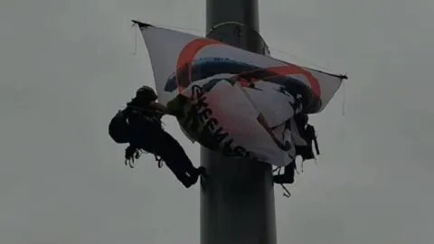 Activistas de Greenpeace escalan asta del Zócalo; protestan contra planta de amoniaco en Sinaloa