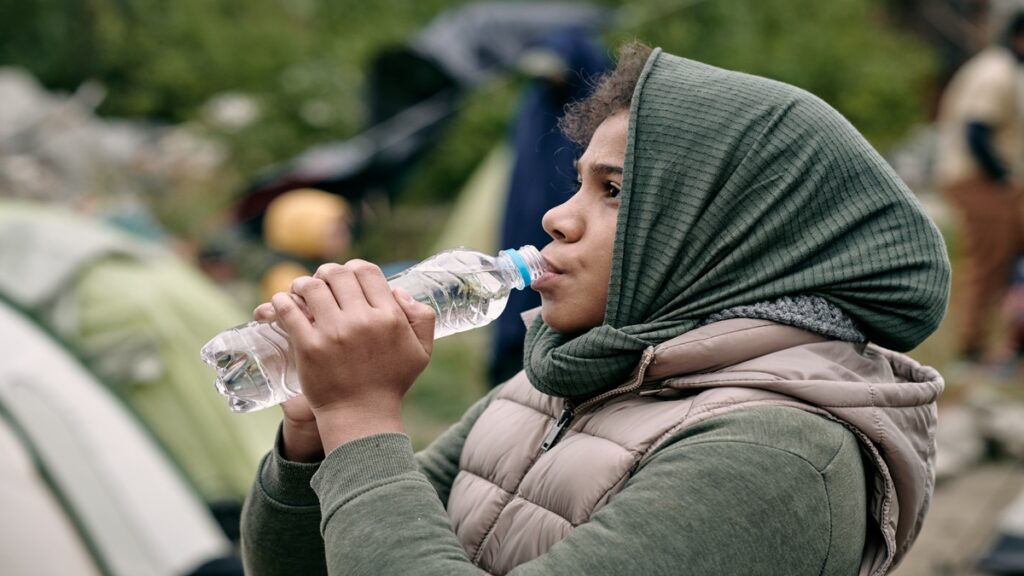 Migrante toma agua en California. Foto: Envato.